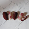 Set of four nail polish samples with floral designs on a tiled floor.
