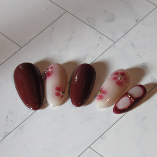 Set of four nail polish samples with floral designs on a tiled floor.